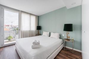 Un dormitorio con una gran cama blanca y una ventana en GuestReady - Porto Experience near Aliados, en Oporto