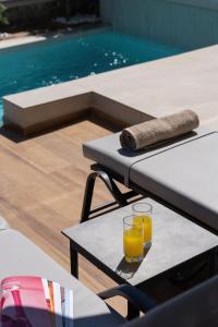 a glass of orange juice on a table next to a pool at Nemesis Villas in Plakias