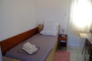 a bed with two towels on it in a room at Small farmhouse by M in Egina