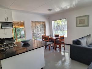a kitchen and living room with a table and chairs at Siesta Cottage in Howick