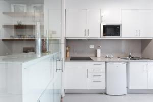 una cucina bianca con armadi bianchi e lavandino di GuestReady - Bright Studio with balcony a Vila Nova de Gaia