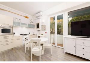 biała kuchnia ze stołem i telewizorem w obiekcie Diamante Sea Apartment w mieście Varigotti