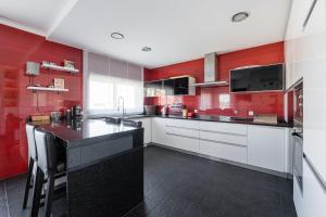 a red kitchen with white cabinets and a black counter at GuestReady - A fantastic retreat in Valongo in Valongo