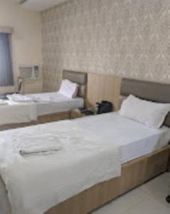 a hotel room with two beds with white sheets at Hotel Richi Regency Bhubaneswar in Bhubaneshwar