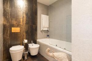 a bathroom with a toilet and a bath tub at GuestReady - Freixo lux with Douro River view in Porto +20 photos