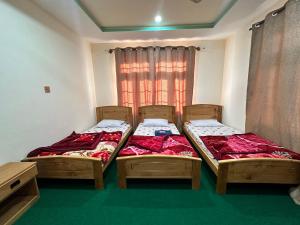 two twin beds in a room with a window at Indus Cabana Guest House and resort in Skardu