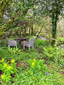 2 bancs et une table dans un jardin fleuri dans l'établissement Shepherds Hut Glamping, à Bantry