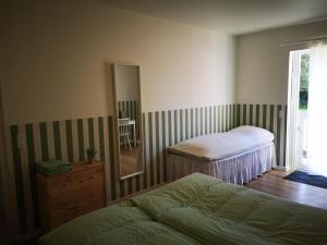 a bedroom with two beds and a mirror and a window at Pension Skovly in Tranekær