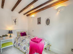 a bedroom with a bed with a pink blanket on it at The Stilts in Bewdley