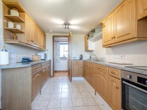 a kitchen with wooden cabinets and a tile floor at Barnstable - Uk46888 in Kilmory