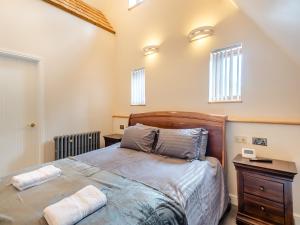 a bedroom with a bed with a wooden headboard and windows at Little Barn At Bradwell Hall in Great Yarmouth