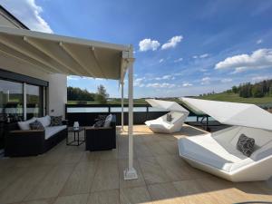 un patio con divani e sedie bianchi sul tetto di Poolhaus Bodensee ideal für Geschäftsreisende a Wasserburg