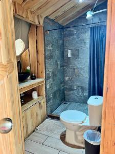 a bathroom with a toilet in a wooden cabin at Green Noise Glamping in Fraijanes