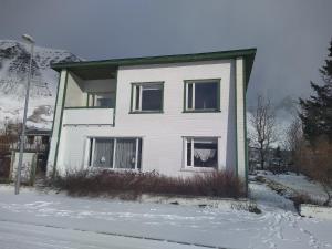 a white house with windows in the snow at Flateyri guesthouse in Flateyri