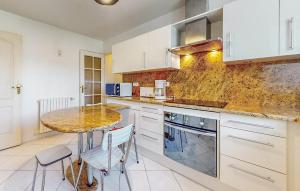 a kitchen with white cabinets and a table and chairs at Awesome Home In Blonville-Sur-Mer in Blonville-sur-Mer