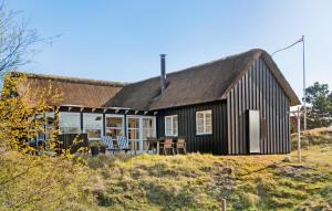 a black cottage with a thatched roof on a hill at Awesome Home In Fan With House A Panoramic View in Fanø