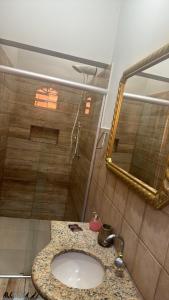een badkamer met een wastafel en een douche met een spiegel bij HOTEL POUSADA MACHADO in Frutal