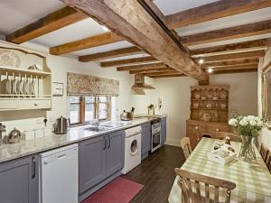 uma cozinha com tectos em madeira e uma mesa com um lavatório em Courtyard Cottage - Uk47218 em Great Bolas