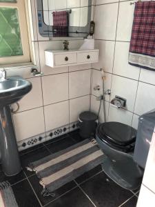 a bathroom with a black toilet and a sink at Casa Moinhos de Vento Vintage in Porto Alegre