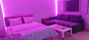 a pink room with a bed and a couch at Monda Apartment in Piraeus