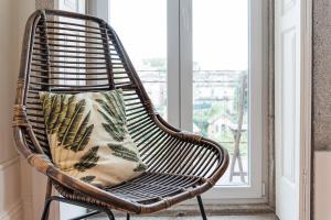 een rotan stoel met een kussen in een raam bij GuestReady - Swallows Nest in Porto