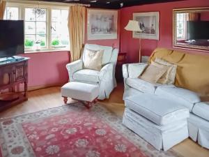 a living room with two white chairs and a tv at Pipers Cottage in Beyton
