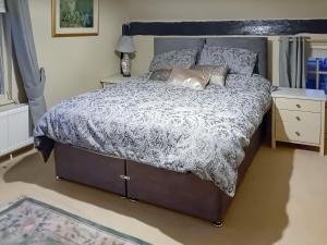 - une chambre avec un lit et une couette grise et blanche dans l'établissement Pipers Cottage, à Beyton