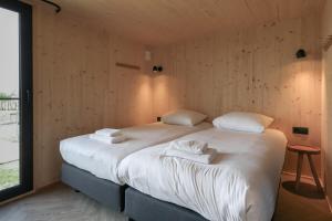 - une chambre avec un grand lit et des serviettes dans l'établissement Hello Zeeland - Tiny House Zeeuwse Liefde 2, à Westkapelle