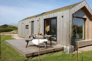a small grey building with a picnic table on a deck at Hello Zeeland - Tiny House Zeeuwse Liefde 2 in Westkapelle