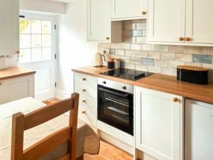 uma cozinha com armários brancos e um forno com placa de fogão em Causeway Cottage em Wolsingham