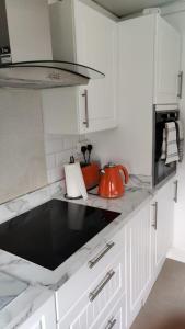 a kitchen with white cabinets and an orange tea kettle at 2 bed Solihull near NEC Airport, JLR, Resort Wrld in Solihull
