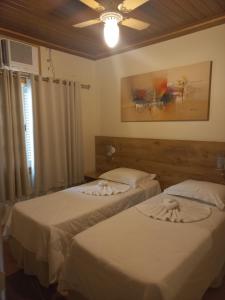 a bedroom with two beds and a ceiling fan at Pousada Eco Da Montanha in Passa Quatro +37 photos
