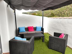 un porche con 2 sillas y un sofá con almohadas coloridas en Casa Rural La Escapadita en Benaoján