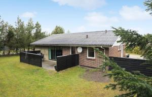 een klein bakstenen huis met zwarte poorten in een tuin bij 3 Bedroom Nice Home In Skjern in Stavning
