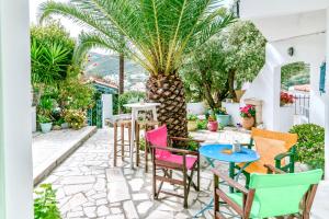 un patio con sillas coloridas y una palmera en Patras Apartments en Fourni Ikarias