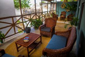 a balcony with wicker chairs and a table with a book at Firefly West Wing in Bagamoyo