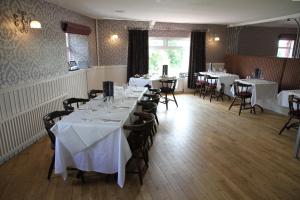 a dining room with tables and chairs with white table cloth at 5 Corners Guest Inn in Ballyclare