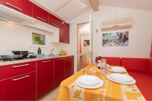 una cocina con armarios rojos y una mesa con platos. en Camping Village VERDEMARE SRL, en Fermo