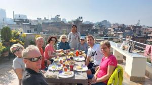 un grupo de personas sentadas alrededor de una mesa comiendo comida en Shine Homestay Famille Francophone - Shine Home and Apartment, en Katmandú