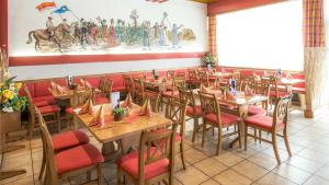 uma sala de jantar com mesas de madeira e cadeiras vermelhas em Gasthof Menüwirt em Sankt Kanzian