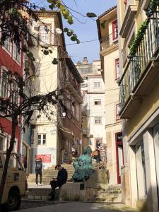 um homem sentado nos degraus de uma rua com uma estátua em Quebra Costas House em Coimbra