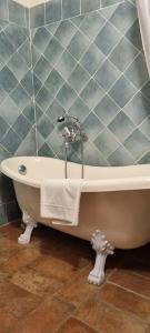 een badkamer met een bad en een betegelde muur bij Oasi nel cuore del Chianti in San Sano
