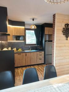a kitchen with wooden cabinets and black walls at Domek na Hubce II in Maniowy