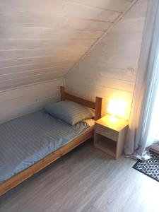 sypialnia z łóżkiem i nocną szafką z lampką w obiekcie Anetta Domki Mielno w mieście Mielno