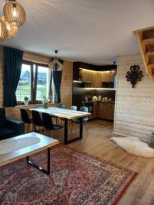 a living room with a table and chairs and a rug at Domek na Hubce II in Maniowy