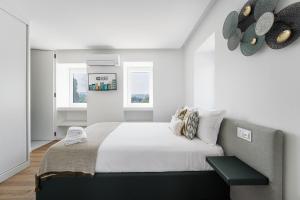 ein weißes Schlafzimmer mit einem Bett und zwei Fenstern in der Unterkunft GuestReady - Villa Stay Luxury Property in Anais