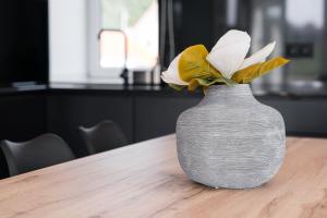 eine graue Vase mit einer weißen Blume darin auf einem Tisch in der Unterkunft GuestReady - Villa Stay Luxury Property in Anais