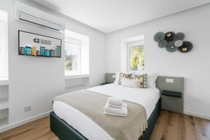 ein weißes Schlafzimmer mit einem Bett und zwei Fenstern in der Unterkunft GuestReady - Villa Stay Luxury Property in Anais