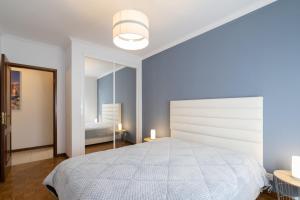 - une chambre blanche avec un grand lit et un miroir dans l'établissement GuestReady - Bright and Modern 2BR Flat in Vila Nova de Gaia, à Porto