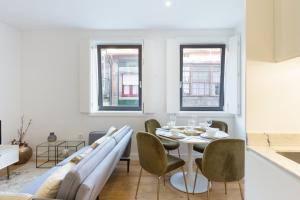 a dining room with a table and chairs and two windows at GuestReady - Cosy and Modern Apartment 4mins from Metro in Porto